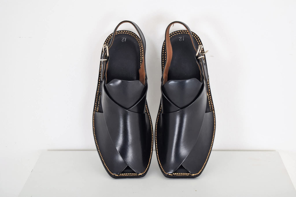 Pair of black leather shoes with brown accents on a white background